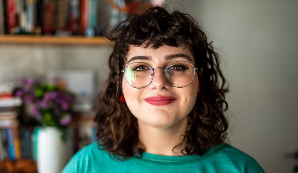 Woman in green top and glasses smiling at camera